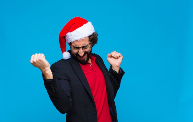 Junger verrückter bärtiger Mann mit Sankt-Hut. Weihnachtskonzept