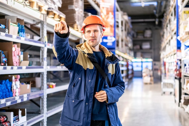 Junger Vorarbeiter im Helm leitet Arbeiten am riesigen Lager b