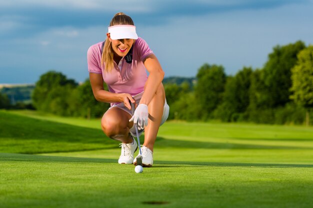 Junger weiblicher Golfspieler auf dem Kurs, der sie anstrebt, setzte