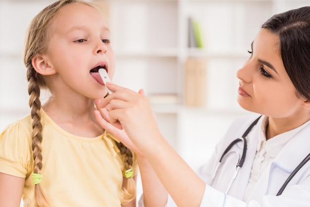 Junger weiblicher Kinderarzt, der ihren kleinen netten Patienten überprüft.