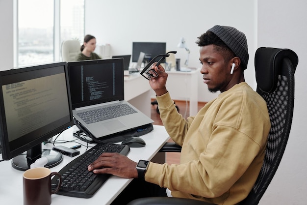 Junger zeitgenössischer afroamerikanischer IT-Ingenieur, der Daten nach Arbeitsplatz dekodiert