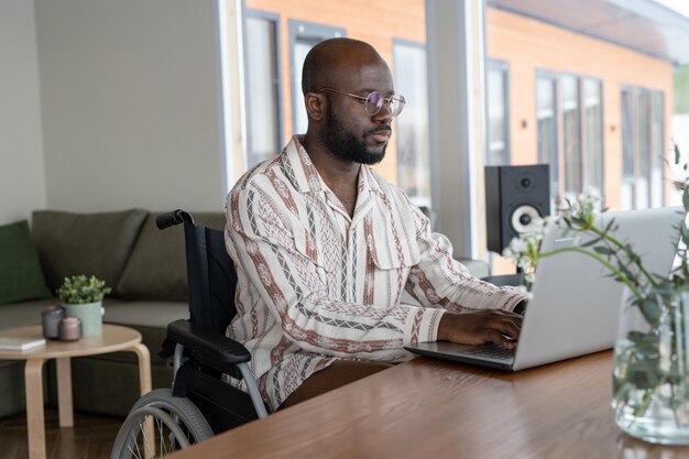 Junger zeitgenössischer Angestellter oder Freiberufler, der vor dem Laptop arbeitet