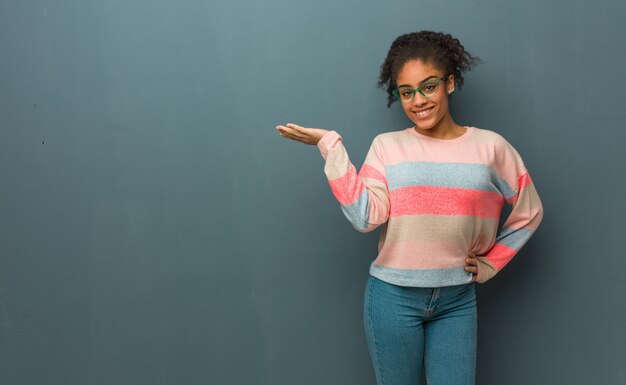 Junges Afroamerikanermädchen mit den blauen Augen, die etwas mit der Hand halten