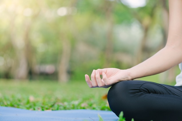 Junges asiatisches Frauenyoga draußen behalten Ruhe und meditiert beim Üben von Yoga