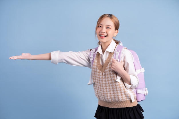 Junges asiatisches Highschool-Mädchen auf blauem Hintergrund