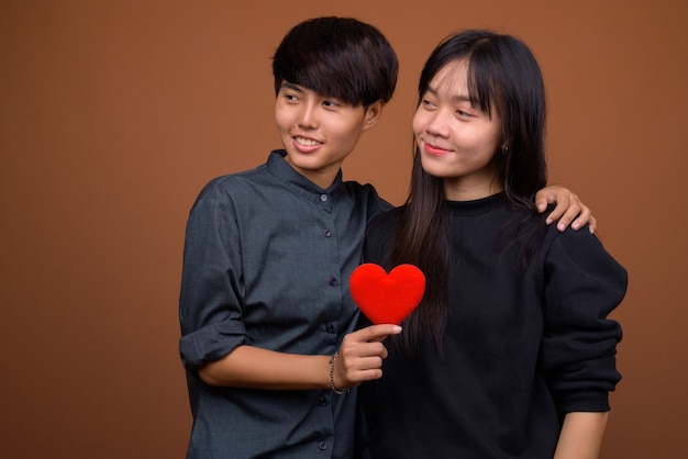 Junges asiatisches lesbenpaar zusammen und verliebt gegen braun