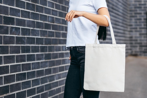 Junges asiatisches Modellmädchen in einem T-Shirt auf der Straße mit weißem Öko-Taschenmodell