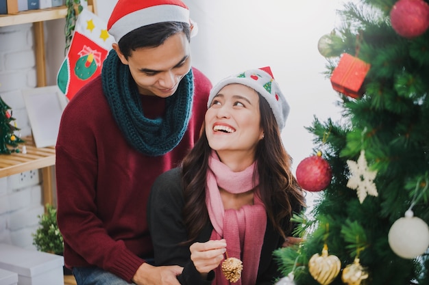 Junges asiatisches Paar, das einen Weihnachtsbaum verziert