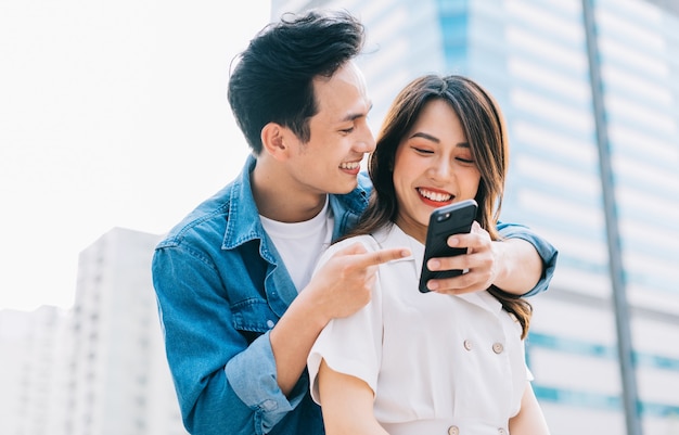 Junges asiatisches Paar, das Smartphone zusammen auf der Straße verwendet