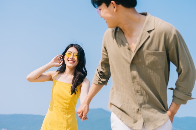 Junges asiatisches Paar, das Sommerferien am Strand genießt