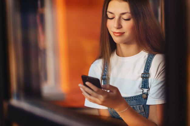 Junges attraktives hübsches Mädchen am Café mit Kaffee- und Telefonthrouthfensterglas