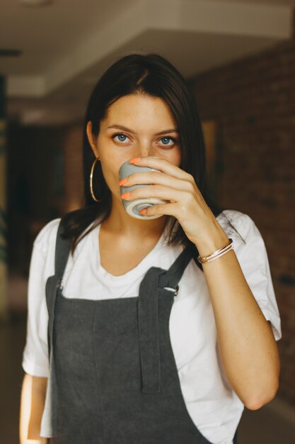 Junges attraktives mädchen in der zufälligen kleidung kaffee im café trinkend