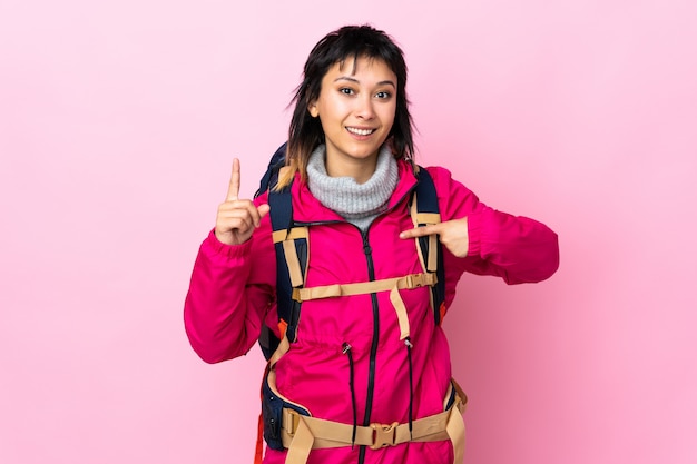 Foto junges bergsteigermädchen mit einem großen rucksack über isolierter rosa wand mit überraschendem gesichtsausdruck