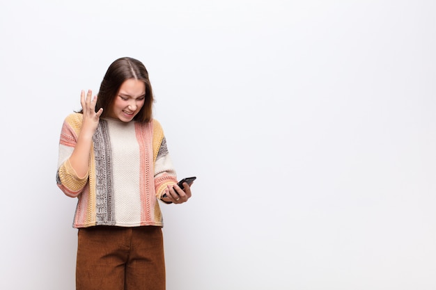 Junges blondes hübsches Mädchen, das ein Smartphone hält