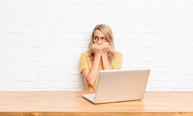 junges blondes Mädchen am Laptop, das besorgt und ängstlich aussieht