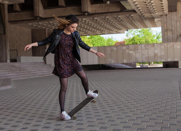 Junges blondes Mädchen, das das Skateboard reitet