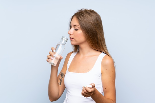 Junges blondes Mädchen mit einer Flasche Wasser über getrenntem Hintergrund