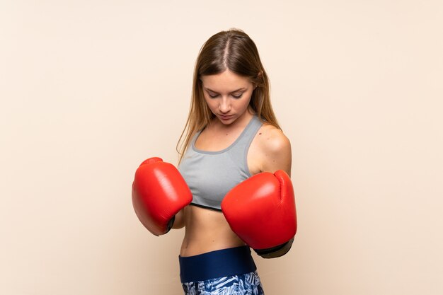 Junges blondes Sportmädchen über lokalisiertem Hintergrund mit Boxhandschuhen