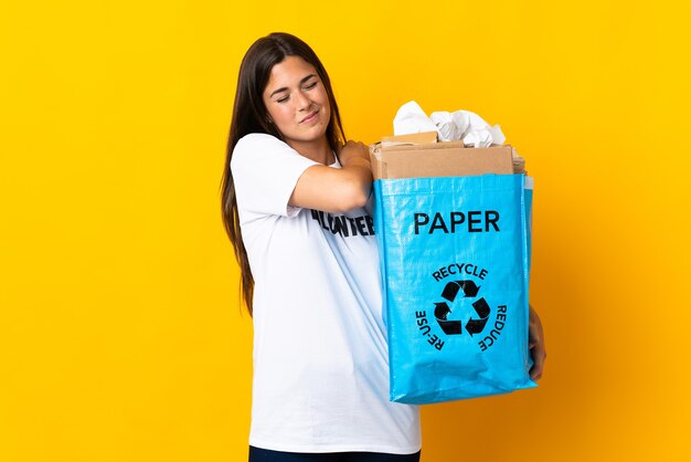 Junges brasilianisches Mädchen, das einen Recyclingbeutel voll Papier hält, um isoliert zu recyceln