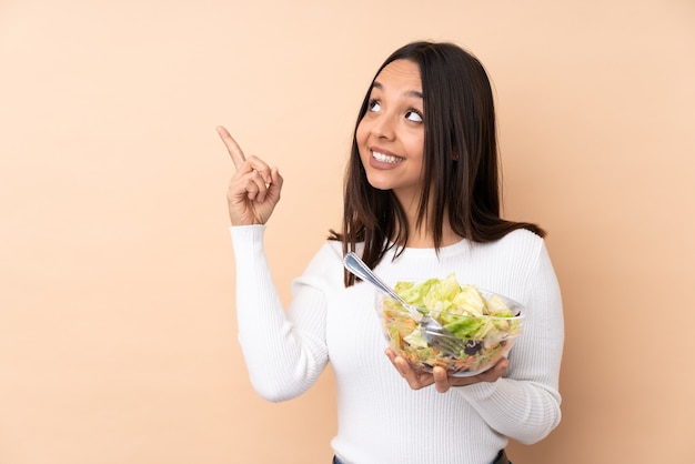 Junges brünettes Mädchen, das einen Salat lokalisiert hält