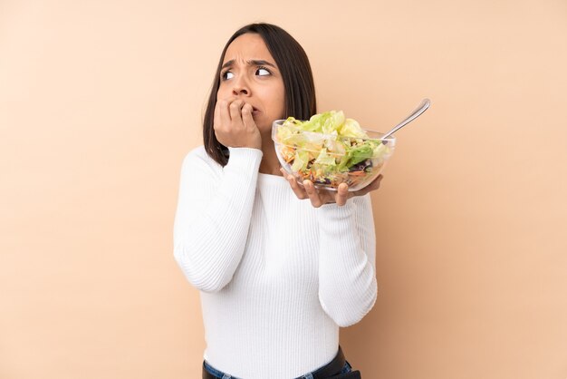 Junges brünettes Mädchen, das einen Salat lokalisiert hält