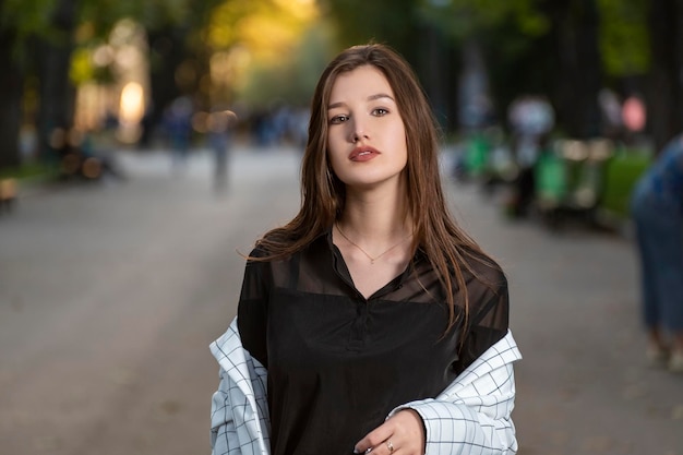 Junges brünettes Mädchen mit braunen Augen und schöner Haut im Hintergrund des Parks Porträt von sexy Rabenhaarigen