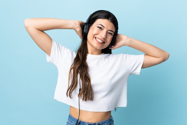 Junges brünettes Mädchen über der blauen Wand, die Musik hört