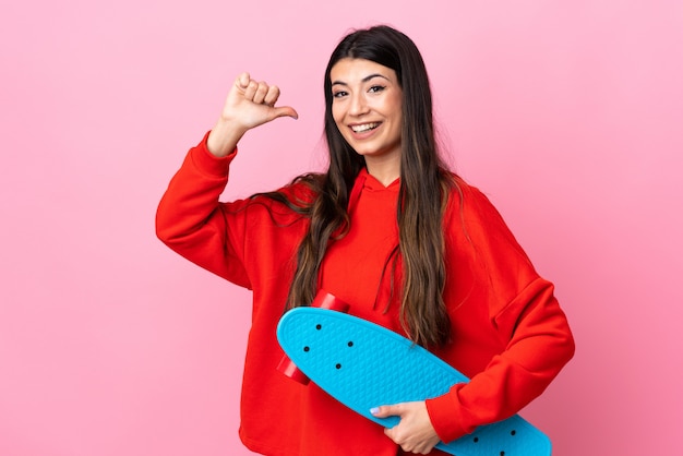 Junges brünettes Mädchen über rosa Wand mit einem Schlittschuh mit glücklichem Ausdruck