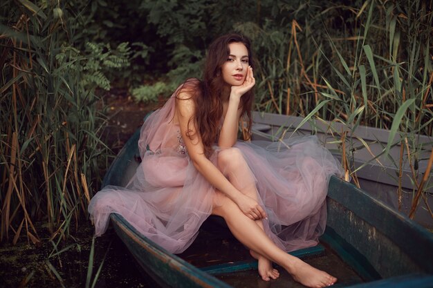 Foto junges brünettes modell mit rosa kleid in einem boot