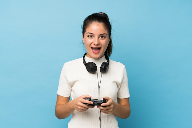 Junges Brunettemädchen über dem lokalisierten Blau, das an den Videospielen spielt