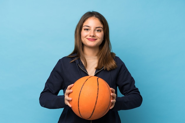 Junges Brunettemädchen über getrenntem Blau mit Kugel des Basketballs