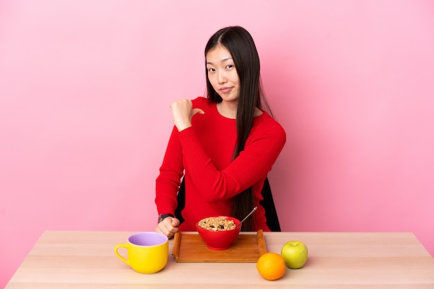 Junges chinesisches Mädchen, das Frühstück in einem Tisch stolz und selbstzufrieden ist