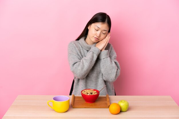 Junges chinesisches Mädchen, das Frühstück in einer Tabelle hat