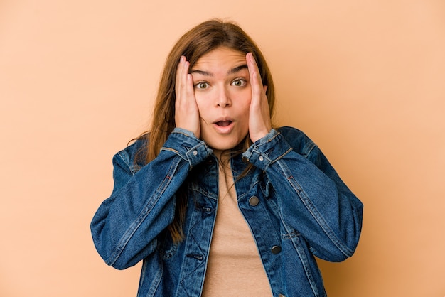 Junges dünnes kaukasisches Teenager-Mädchen, das Spaß hat, die Hälfte des Gesichts mit Handfläche bedeckend.