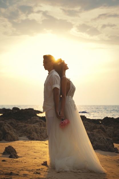 Junges Ehepaar in Umarmung feiert ihre Hochzeit am Strand