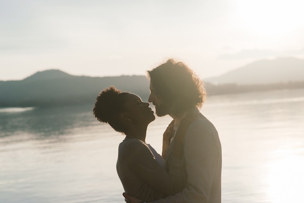 Junges erwachsenes interracial Paar auf einem Strand, kaukasischer Mann und Afroamerikanerfrau in der Freizeitkleidung, die Sommertag am Meerufer genießt