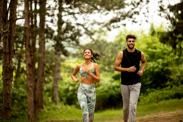 Junges Fitnesspaar, das an einem Sommertag auf dem Waldweg läuft