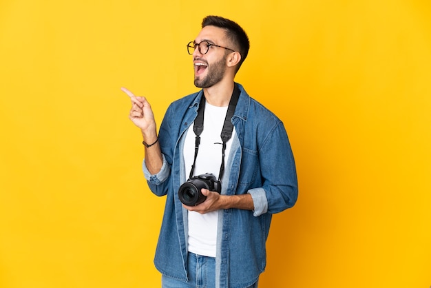 Junges Fotografmädchen lokalisiert auf gelbem Hintergrund, das beabsichtigt, die Lösung beim Anheben eines Fingers zu realisieren