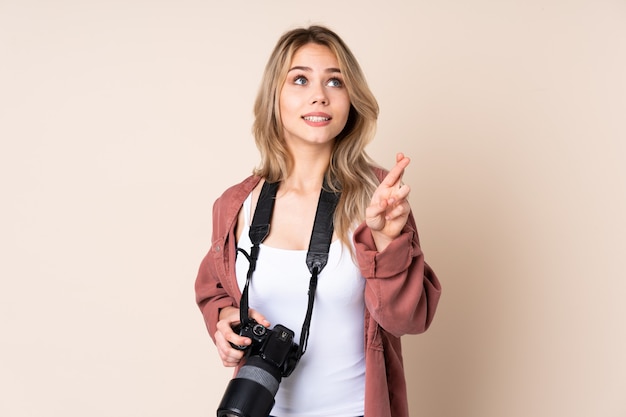 Junges Fotografmädchen über Wand mit den Fingern kreuzend und wünschend das Beste