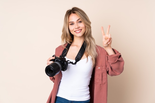 Foto junges fotografmädchen über wand zeigt siegeszeichen mit beiden händen