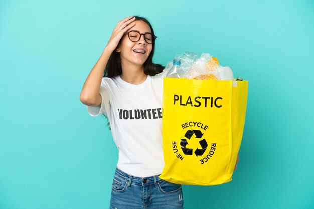 Junges französisches Mädchen, das eine Tasche voller Plastikflaschen hält, um viel lächelnd zu recyceln