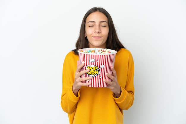 Junges französisches Mädchen lokalisiert auf weißem Hintergrund, der einen großen Eimer Popcorn hält