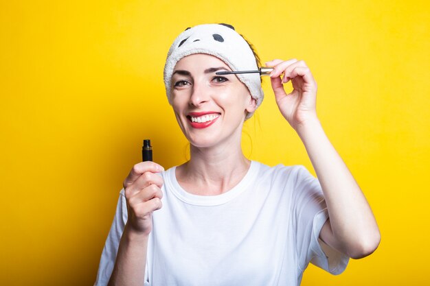 Junges freundliches Mädchen macht Make-up, in einem weißen T-Shirt