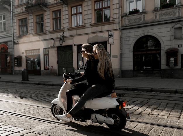 Junges fröhliches Mädchen mit Roller in der europäischen Stadt