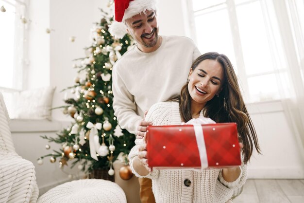 Junges fröhliches Paar verliebt in Geschenk zu Weihnachten