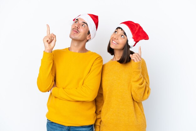 Junges gemischtes Paar, das Weihnachten feiert, isoliert auf weißem Hintergrund, das eine großartige Idee zeigt und nach oben schaut