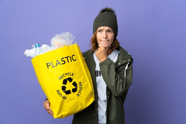 Junges georgisches Mädchen, das eine Tasche voll Plastikflaschen hält, um Zweifel und Denken zu recyceln