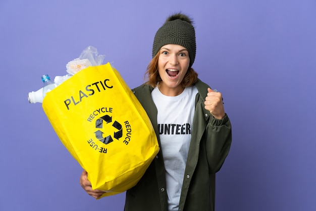 Junges georgisches Mädchen, das eine Tasche voller Plastikflaschen hält, um einen Sieg in der Siegerposition zu recyceln