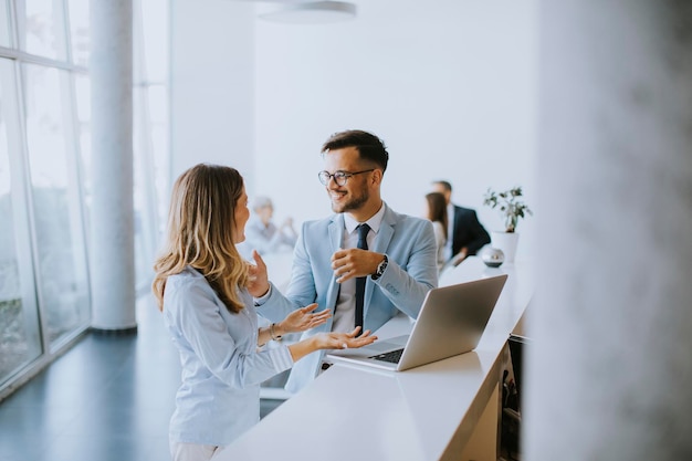 Junges Geschäftspaar arbeitet und diskutiert per Laptop im Büro vor ihrem Team