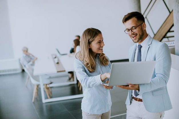 Junges Geschäftspaar arbeitet und diskutiert per Laptop im Büro vor ihrem Team